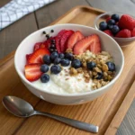 Cottage cheese breakfast bowl topped with fresh berries, banana slices, chia seeds, and honey.