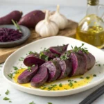 Roasted purple sweet potato cubes with herbs served in a white bowl on a rustic wooden table